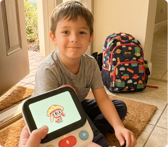 A boy by the front door, backpack on, holding his Nowa device