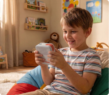 A boy on the sofa, smiling at his Nowa device